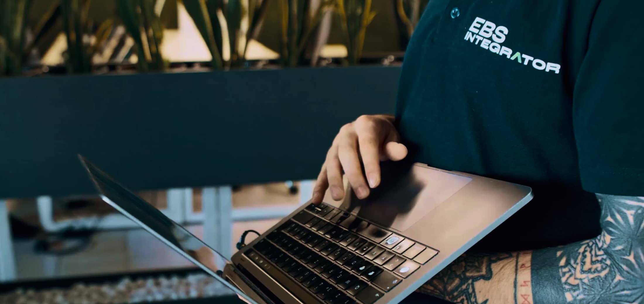 An EBS Integrator employee wearing a black polo shirt with the new company logo designed by TARNOVSKI Branding Studio as part of their rebranding.